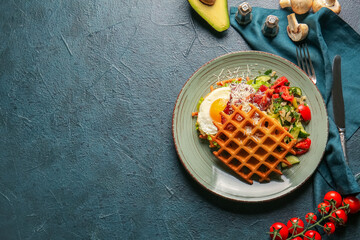 Plate with delicious Belgian waffles and vegetables on dark background