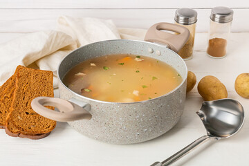 Cooking pot with tasty dumpling soup and ingredients on light wooden background