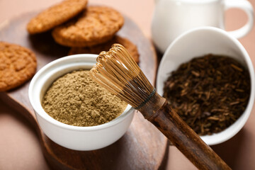 Wooden board with tasty hojicha cookies, powder and chasen on brown background