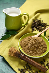 Bowl with hojicha powder and chasen on green background