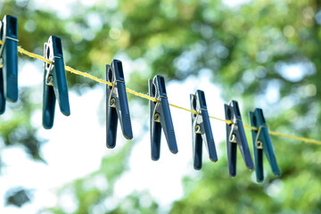 Plastic clothespins hanging on laundry line outdoors, closeup