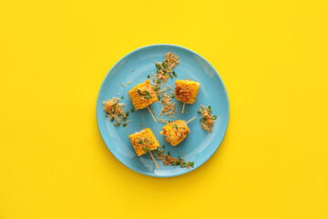 Plate with pieces of delicious Elote Mexican Street Corn on yellow background