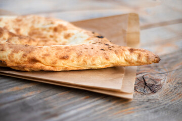 Eastern bread on a paper bag on a wood table. Tandoor lavash. Cake.