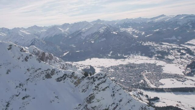 Aerial view over a mountain peak, revealing the Oberstdorf village, winter in sunny Germany