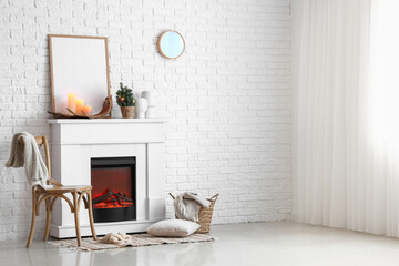 Interior of light room with electric fireplace and small Christmas tree