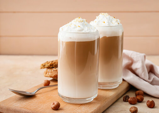 Glasses of tasty latte with nuts on table