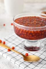 Glass vase with tasty rowan jam on table, closeup