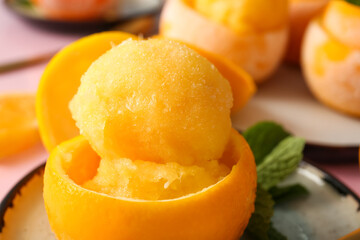 Fototapeta na wymiar Plates with tasty ice creams in orange peels on color background