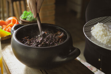 Serving feijoada, a Brazilian dish on a lunch table