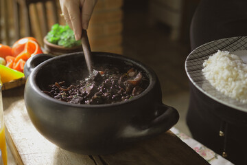 Serving feijoada, a Brazilian dish on a lunch table