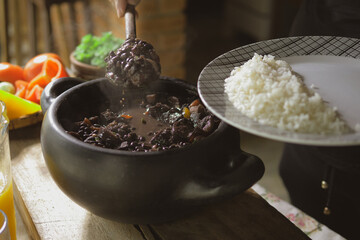 Serving feijoada, a Brazilian dish on a lunch table