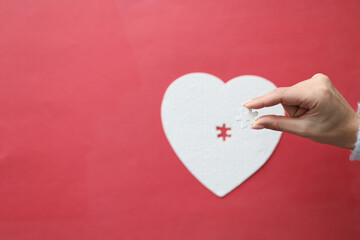 Top view of female hand holding missing piece of heart puzzle jigsaw