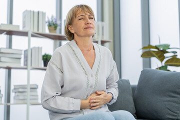 Flatulence caucasian mature adult, senior woman hand in stomach ache, suffer from food poisoning,...