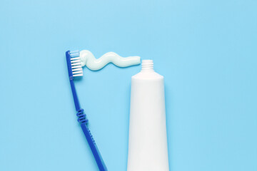 Toothpaste in tube and colored toothbrushes on a blue background. Top view