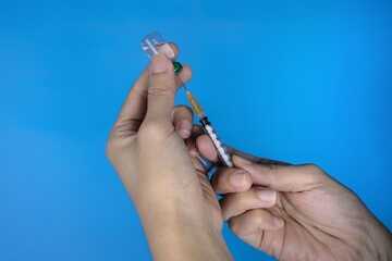 A closeup of doctor's hands holding syringe and a bottle of vaccine. Clear glass vaccine bottle. ...