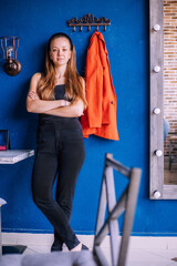 A young woman on the background of a blue wall. A red jacket hangs nearby.