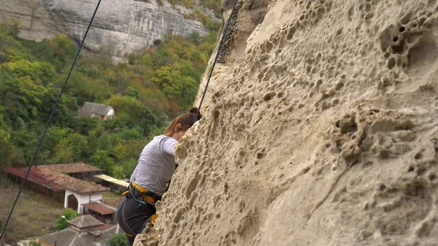 Outdoors rock climbing. Woman confidently rock climbs mountain, fitness lifestyle. Climbing extreme active sport activity