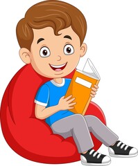 Little boy reading a book and sitting on big pillow