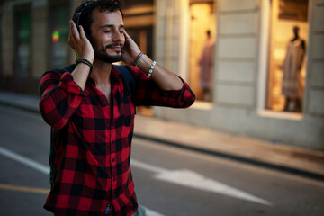 Young man listening to music. Urban fashion man with headphones enjoying the city..