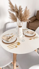 autumn table setting, white dishes, golden cutlery.