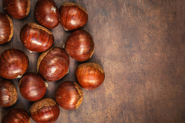 Fototapeta premium Chestnuts on on an old board with copy space. Autumn fall concept. Horse chestnuts top view.