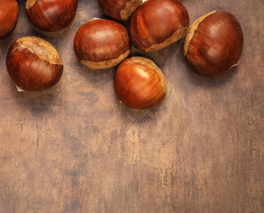 Sweet chestnuts on old rustic wooden table with plenty of copy space. Autumn fall concept. Horse chestnuts top view.