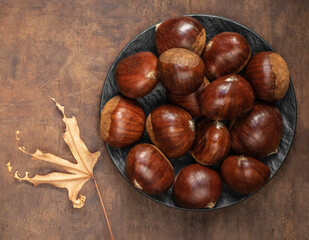 Sweet chestnuts on old rustic wooden table with plenty of copy space. Autumn fall concept. Horse chestnuts top view.