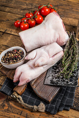 Fresh Raw pork knuckle or hoof,  feet on a butcher board with cleaver. Wooden background. Top view