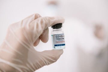 Doctor Hands in protective gloves holding Coronavirus 2019-nCoV Vaccine vial.