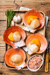 Scallops seafood on a wooden board with salt and herbs. wooden background. Top view