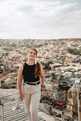 Fototapeta na wymiar A young woman tourist on a view point looks at the city of Goreme in Cappadocia.Turkey. Top attraction travel destinations - Goreme National Park.
