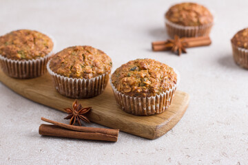 Homemade freshly baked pumpkin muffins with oatmeal and nuts on beige textured background