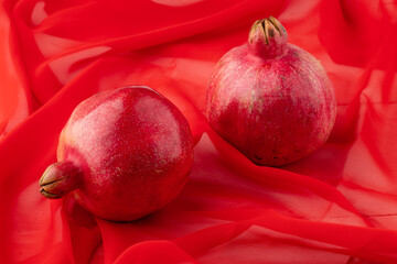 pomegranate fruit with turkish jewellery and open pomegranate on an red, side view