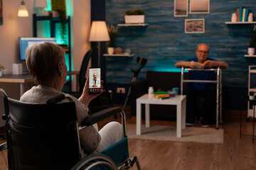 Retired woman talking to doctor on video call conference in living room. Older patient using internet for telemedicine and healthcare checkup with medic while sitting in wheelchair