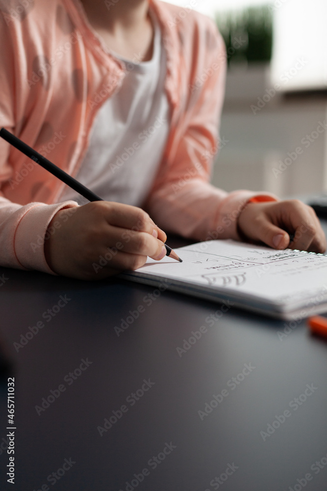 Poster closeup of little schoolchild writing mathematics homework on notebook during classroom lesson sitti