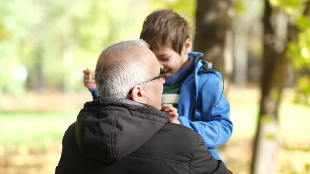 Grandfather and little grandson walking in the autumn park. soft selective focus