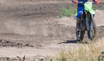 Motocross motor bike driving on race track and throwing up pieces of dirt with the tires