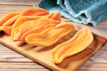 Close-up view of dried mango slices on a wooden board. Selective focus.