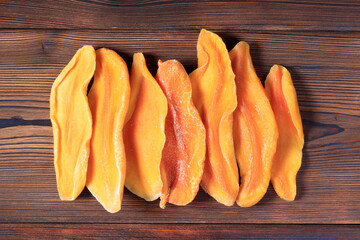 Top view of dried mango slices on wooden background.