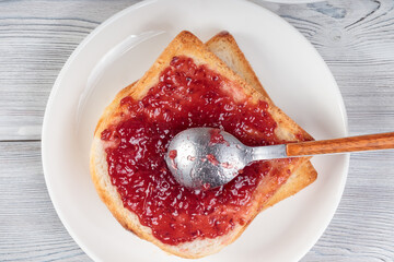 Top view of Raspberry Jam with Toast Bread on white table.