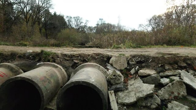Concrete waste pipes. Streams of water flow through concrete pipes. Polluted body of water in the park. Shooting from the drone. Aerial photography.