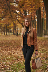 Fototapeta na wymiar young woman in autumn park. yellow trees in the distance