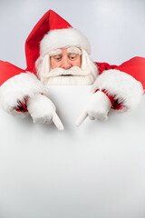 Santa Claus points to white copy space. Advertising. Merry Christmas.
