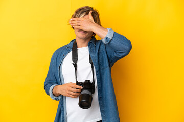 Young photographer man isolated on yellow background covering eyes by hands. Do not want to see something