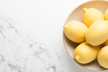 Several yellow bright lemons in a plate on a light background. Bright citruses.