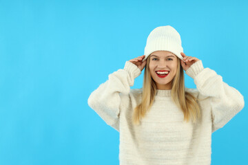 Obraz na płótnie Canvas Attractive girl in woolen hat and sweater on blue background