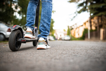 Obraz premium Close up of man's shoes standing on an electrical scooter on the city street