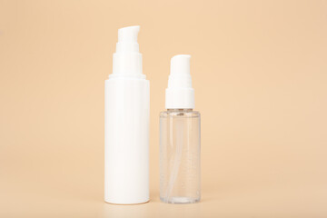 Transparent bottle with liquid face gel or foam and skin cream or lotion against bright beige background with copy space