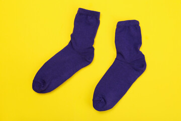 Pair of violet socks on yellow background