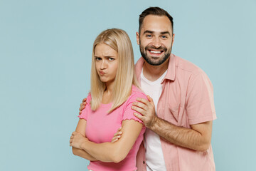 Young sad couple two friends family man sulking woman in casual clothes try to make up after fighting hugging together isolated on pastel plain light blue background studio People lifestyle concept.